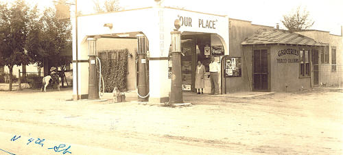 Sepia photo of a small gas station and grocery store with sign: 