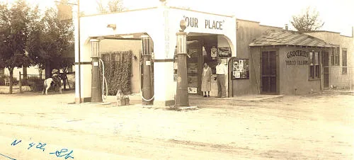 Sepia photo of a small gas station and grocery store with sign: 