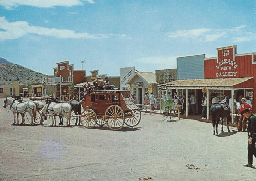 A photograph an old west style line of building fronts with stage coach in foreground.